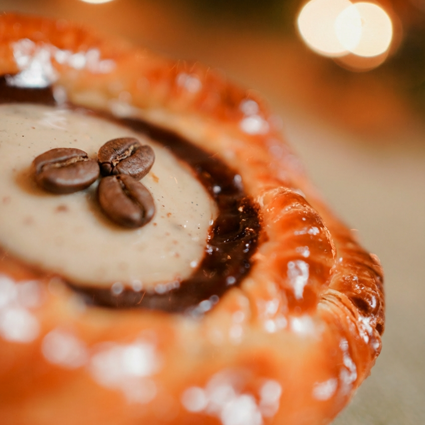 A luxurious Tiramisu Croissant filled with mascarpone cream and espresso-soaked sponge, finished with cocoa. Freshly baked at Yann Haute Patisserie in Calgary.
